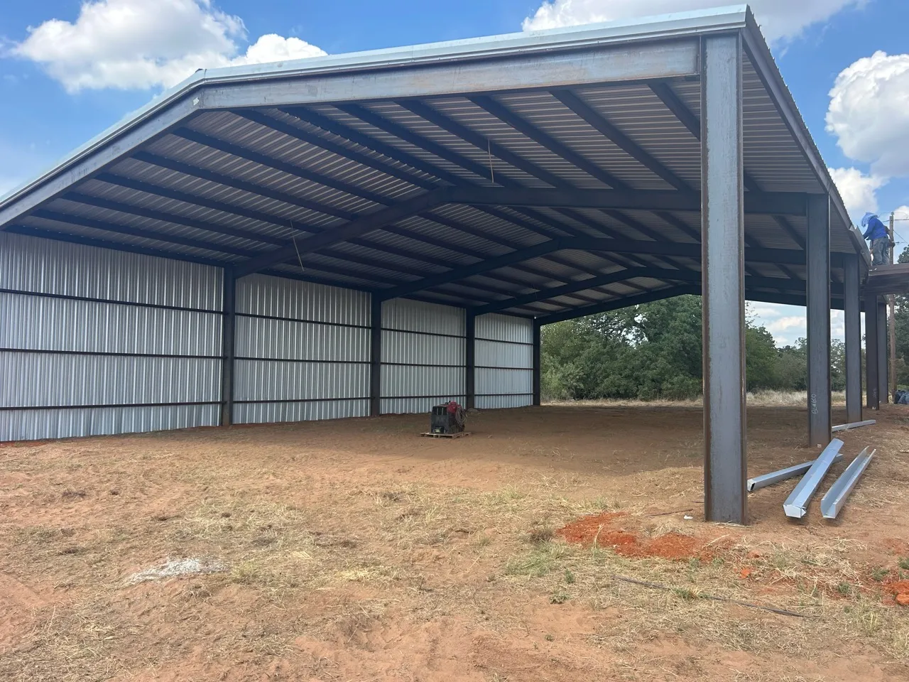 View beneath the new hay barn roof showing steel framing and metal wall panels.
