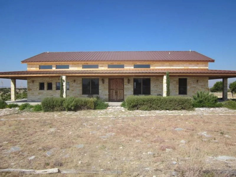 Front elevation of the stone ranch house with covered porch.