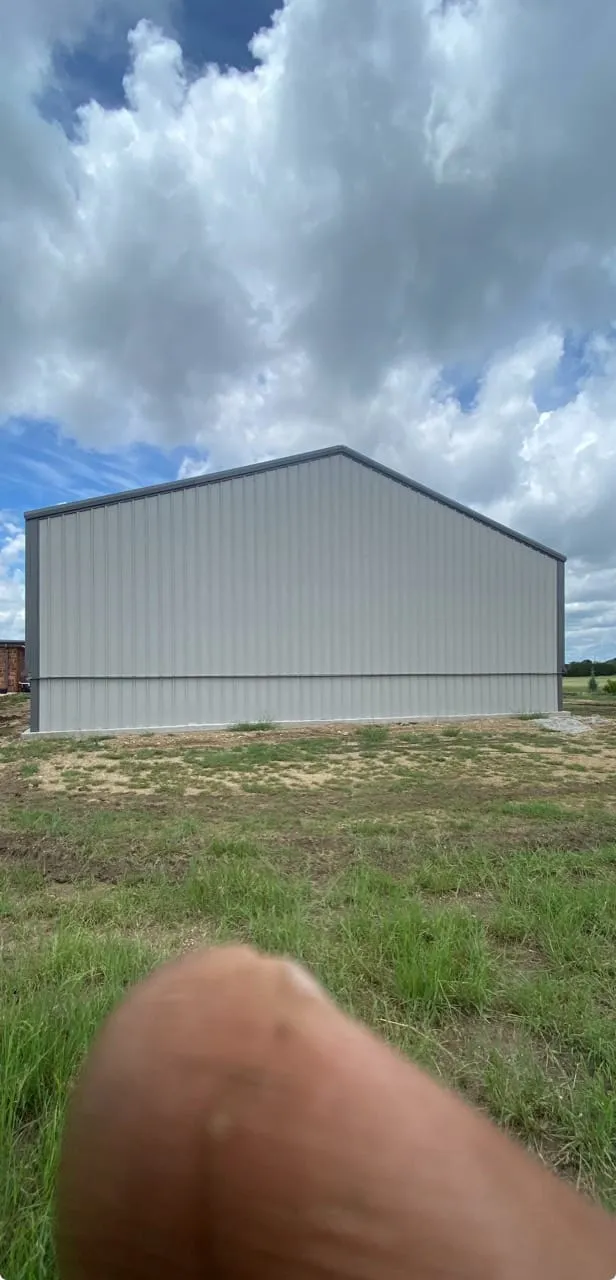 Light-colored metal siding and gable roof on the home gym building in Lometa.