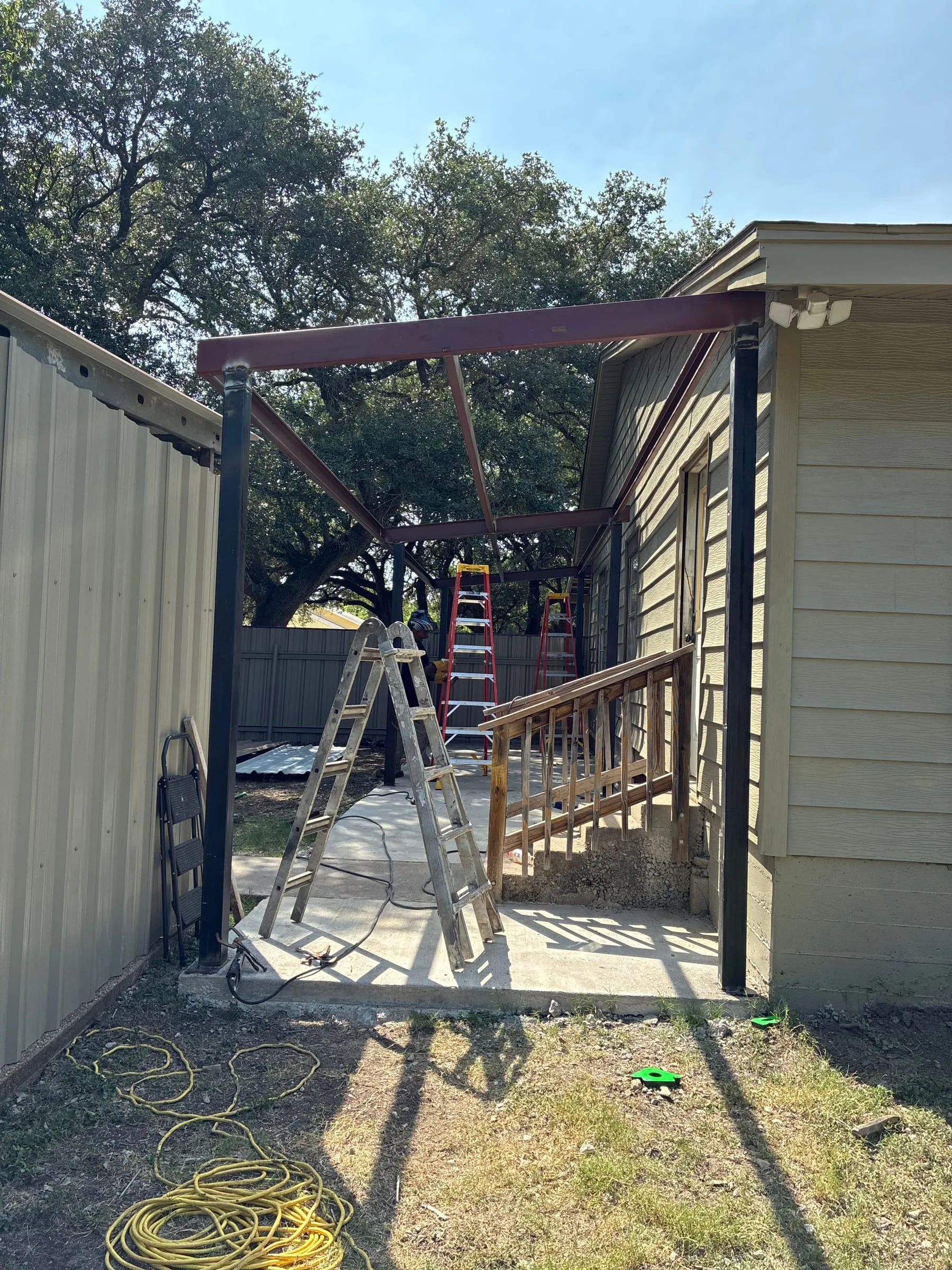 Steel patio frame spanning the concrete walkway beside the home.