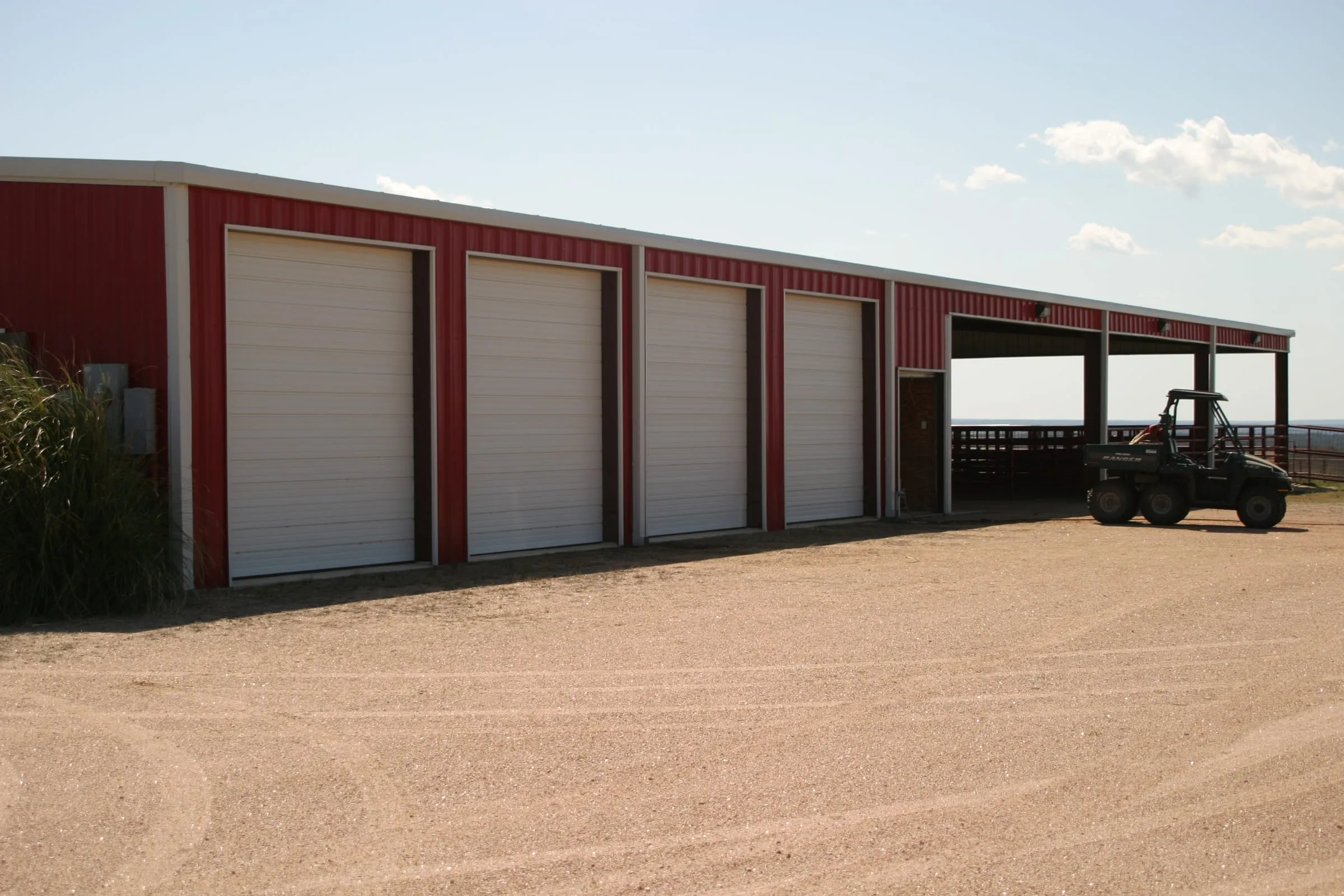 Storage garages with red roll-up doors and gravel drive.