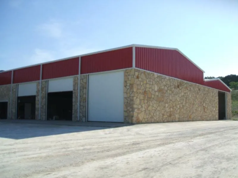 Corner view of the dealership with stone columns and red parapet.