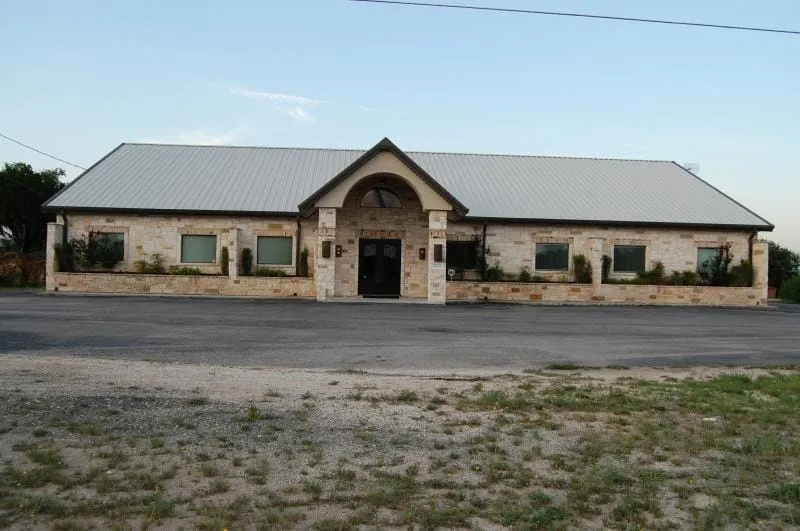 Stone office building with arched entry and metal roof.