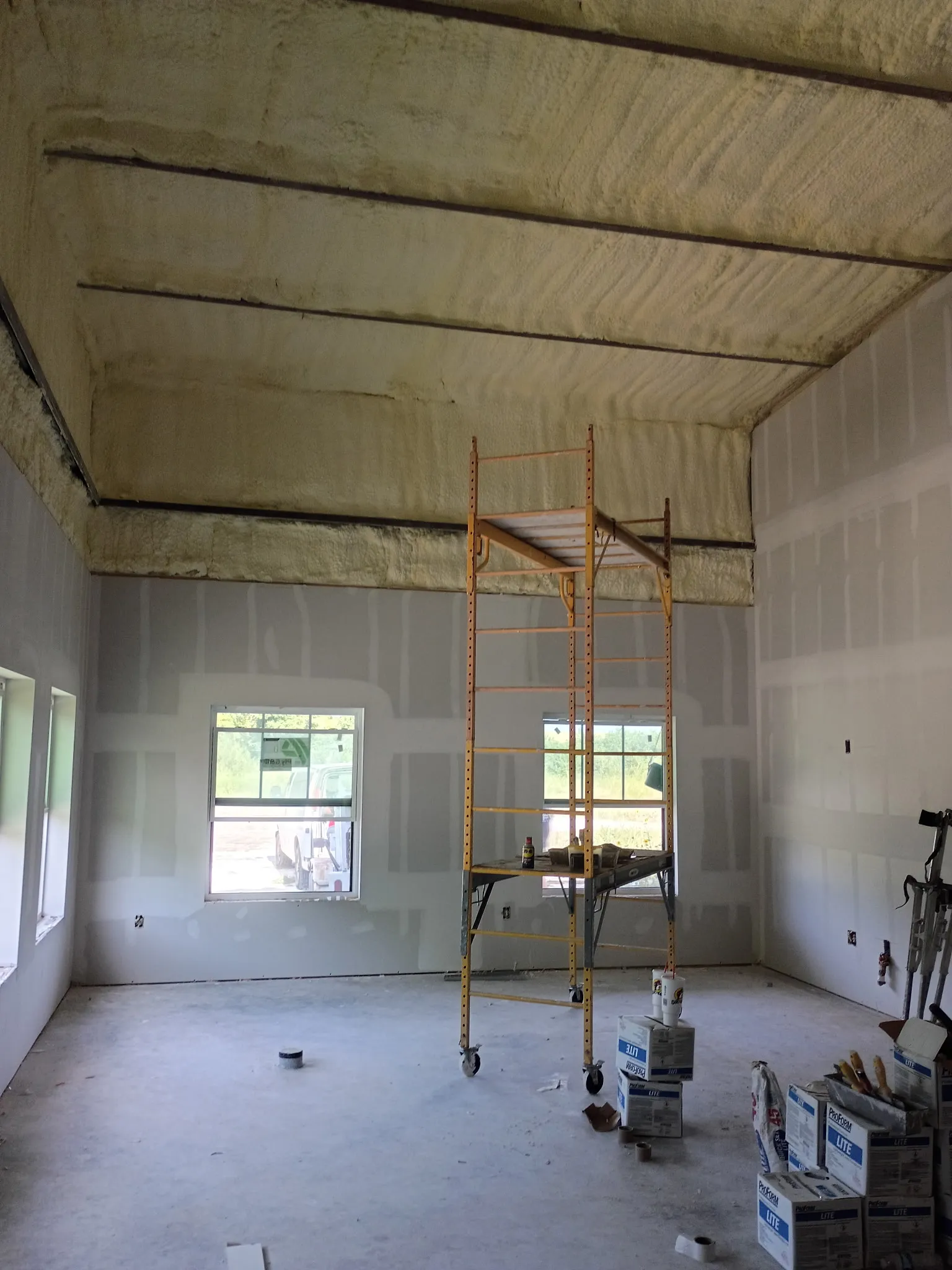 Vaulted barndominium room with finished drywall and spray-foam insulation overhead.