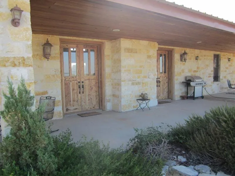 Stone entry with wood double doors and porch lighting.