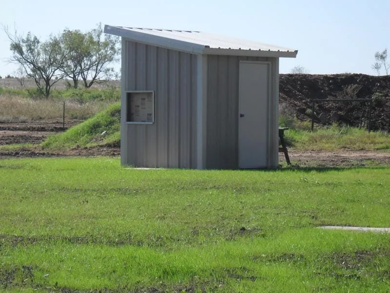 Compact metal shed set on a green pasture.