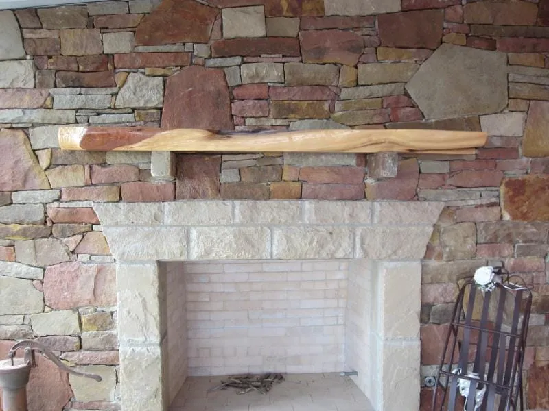 Outdoor stone fireplace with timber mantel.