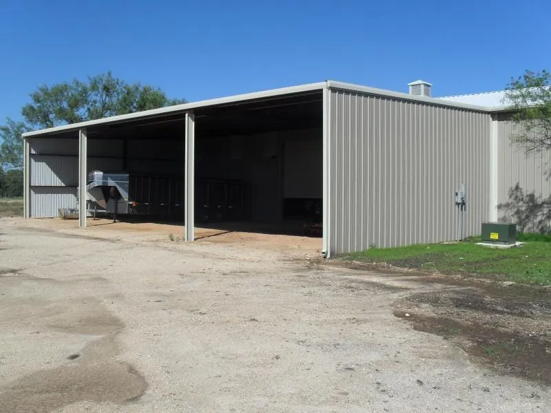 Open equipment barn with gravel approach.