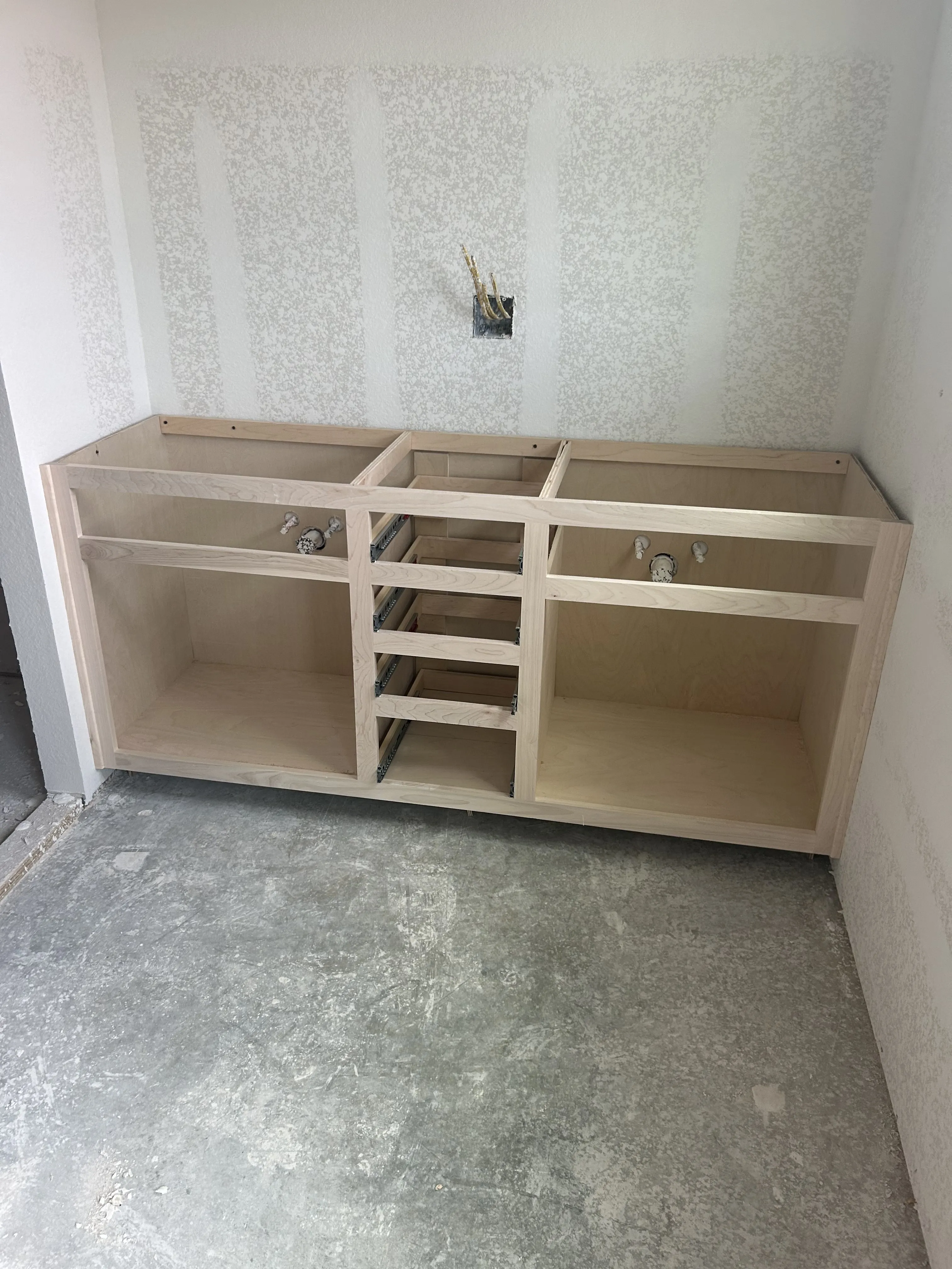 Custom double-vanity cabinet fitted around the bathroom plumbing rough-in.