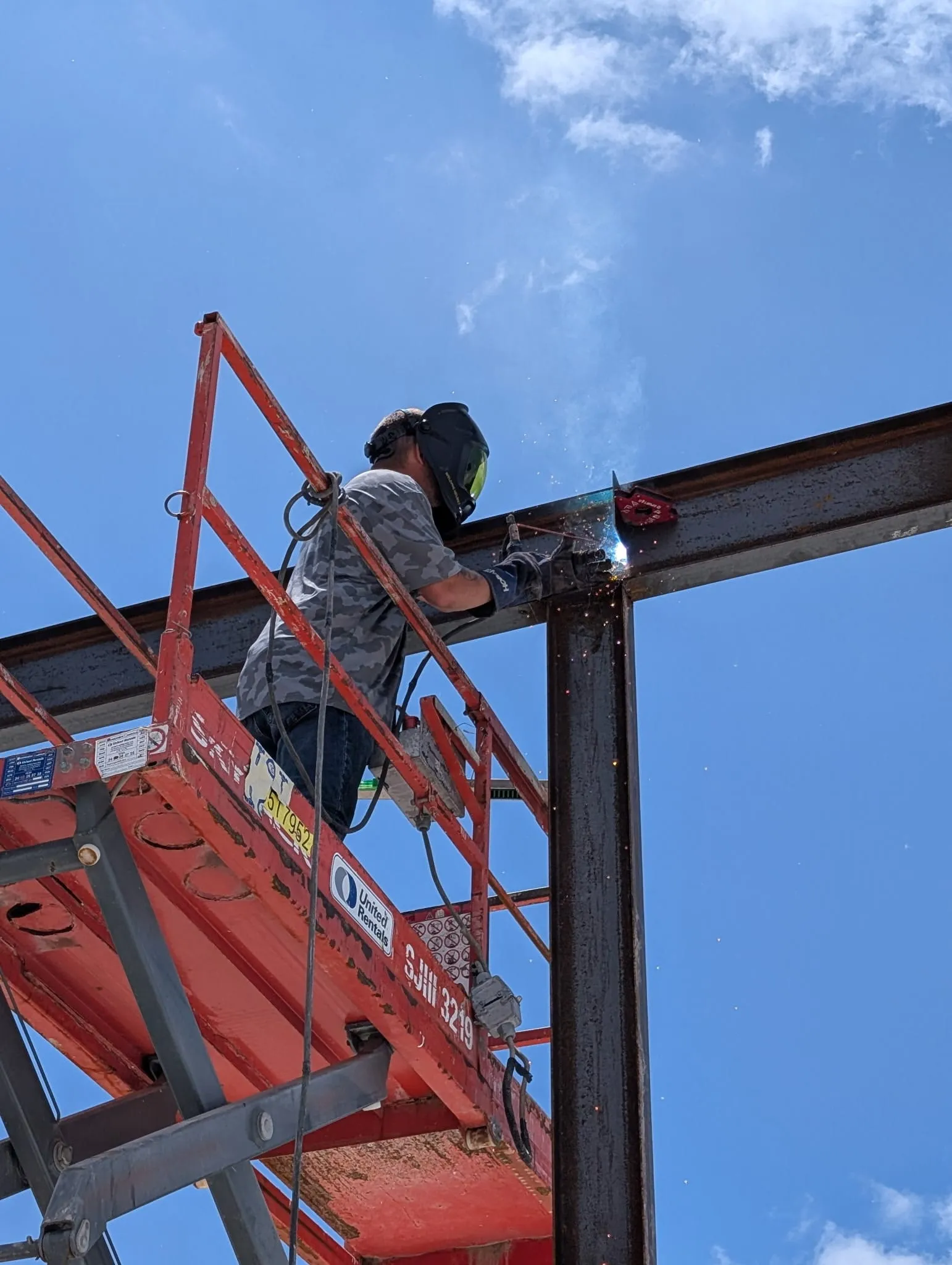 Lift and worker positioned beneath the elevated steel framing.