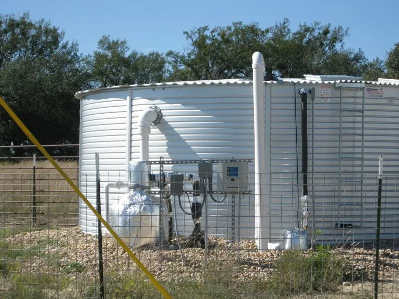 Corrugated steel rainwater collection tank plumbed to a metal roof.
