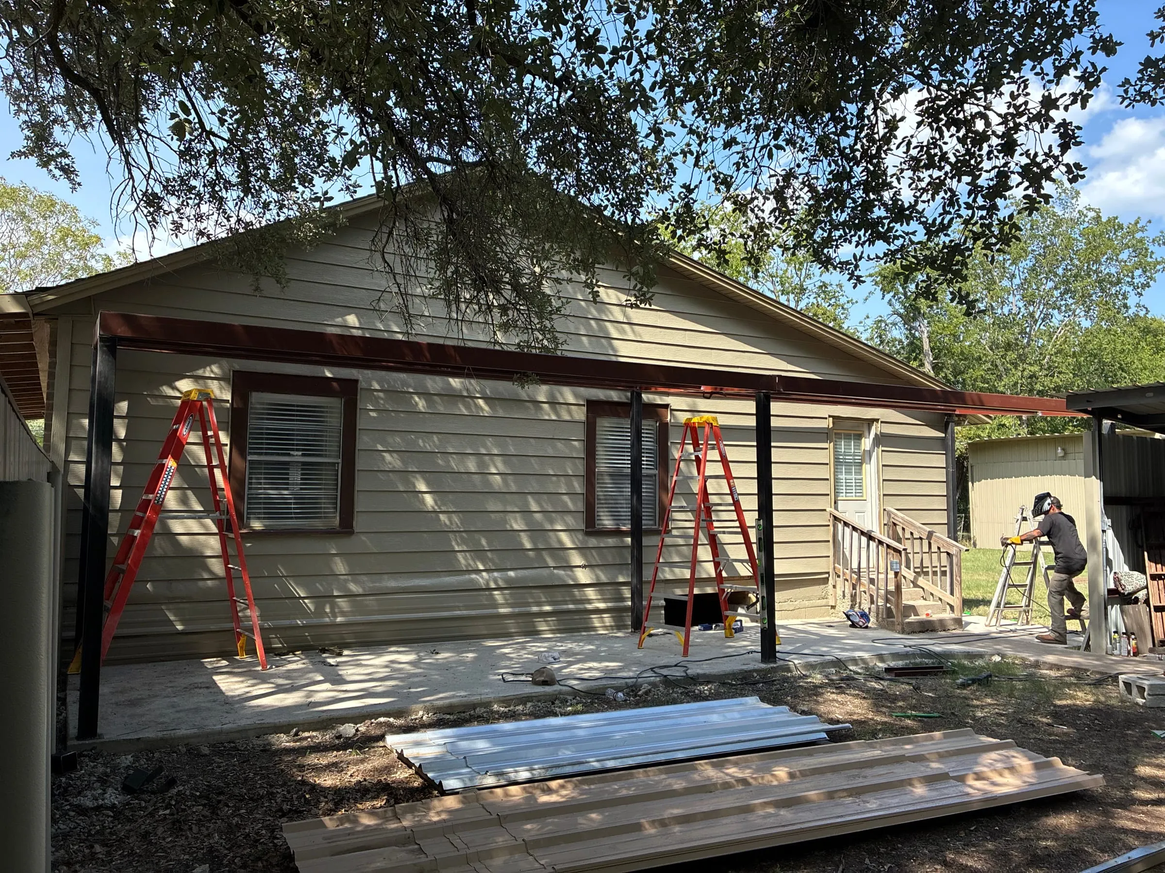 Welded steel patio-cover frame installed beside an existing home.