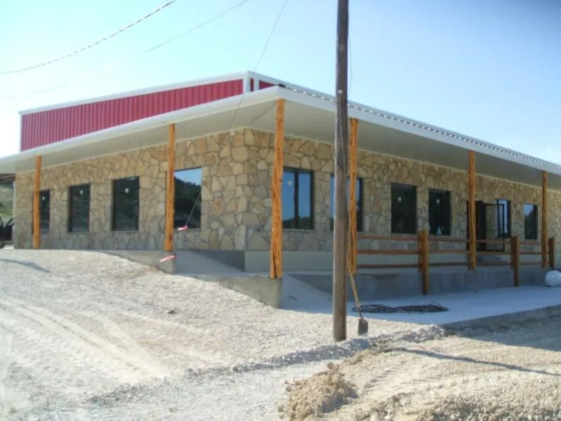 Stone dealership building with red metal trim and covered walk.