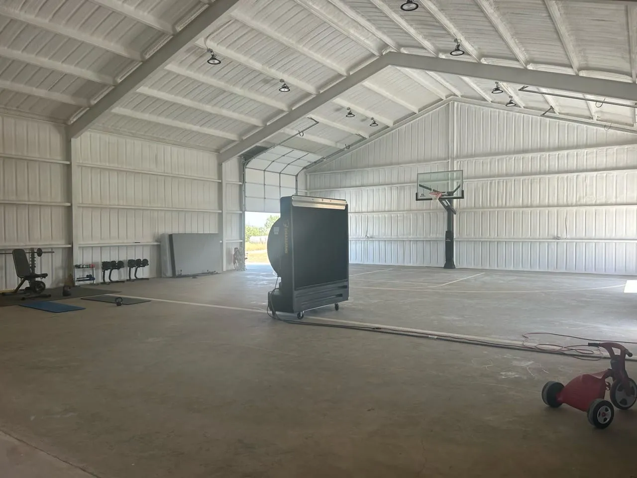 Insulated steel home gym in Lometa with a basketball hoop, court markings, and exercise equipment.